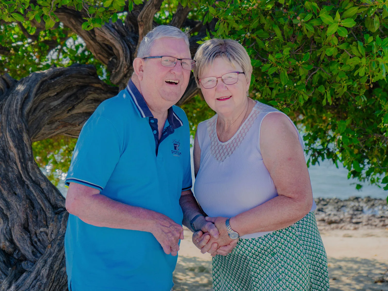 Couple laughing together in front of a twisted tree in Aruba