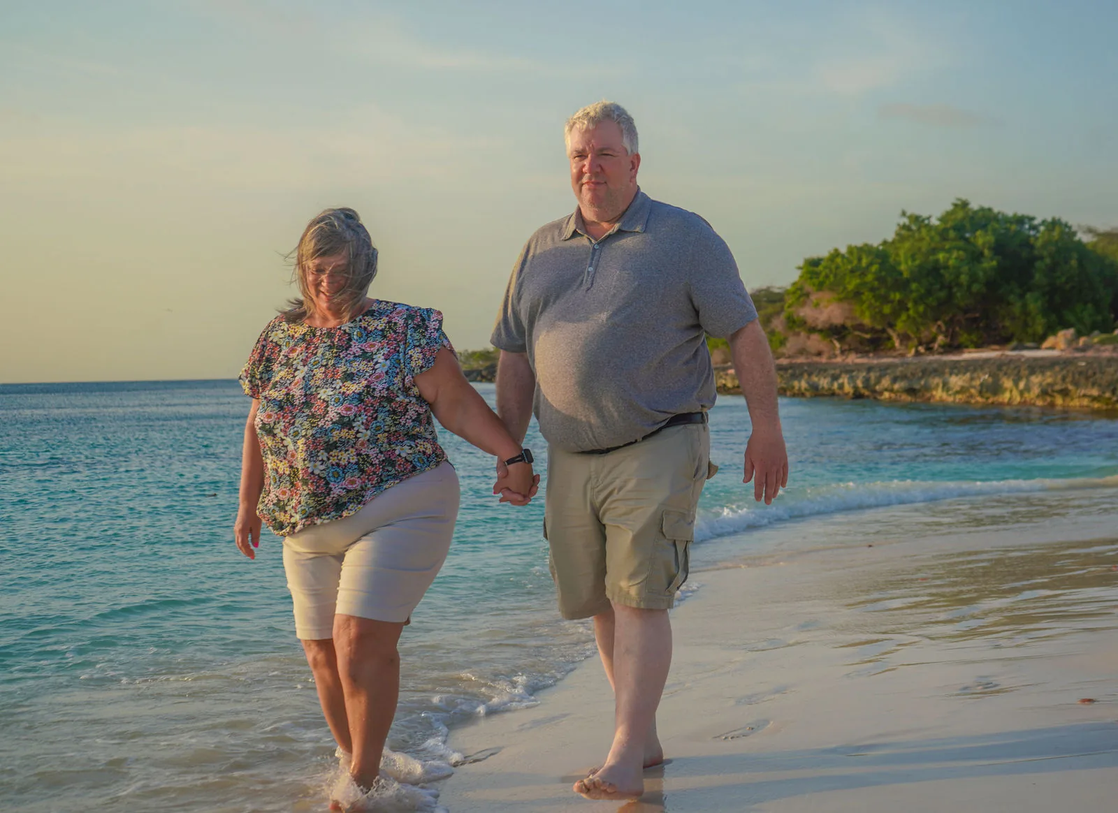 Couple walking hand in hand through the shallow water in Aruba