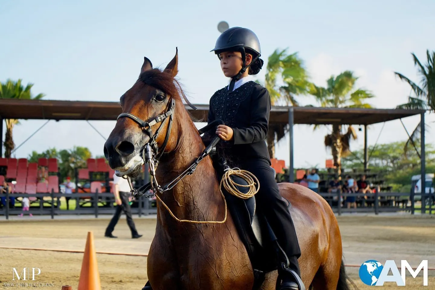 Young rider in a helmet on a horse at an equestrian show in Aruba