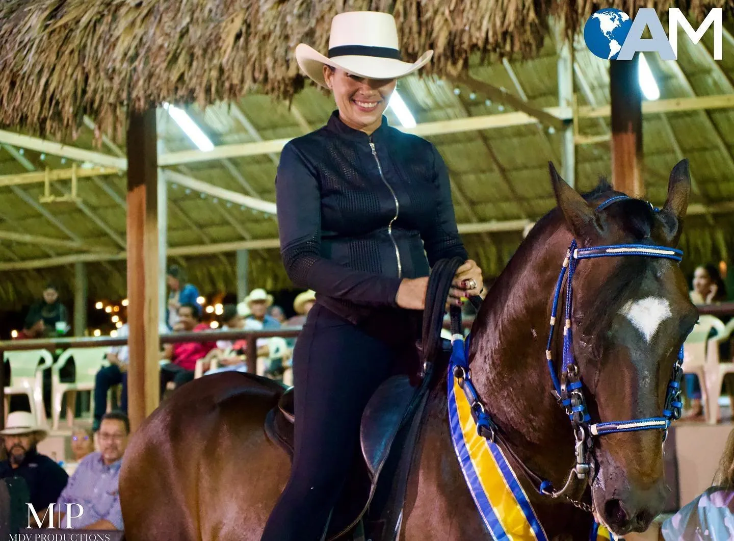 Rider in a white hat smiling on her horse at an equestrian show in Aruba