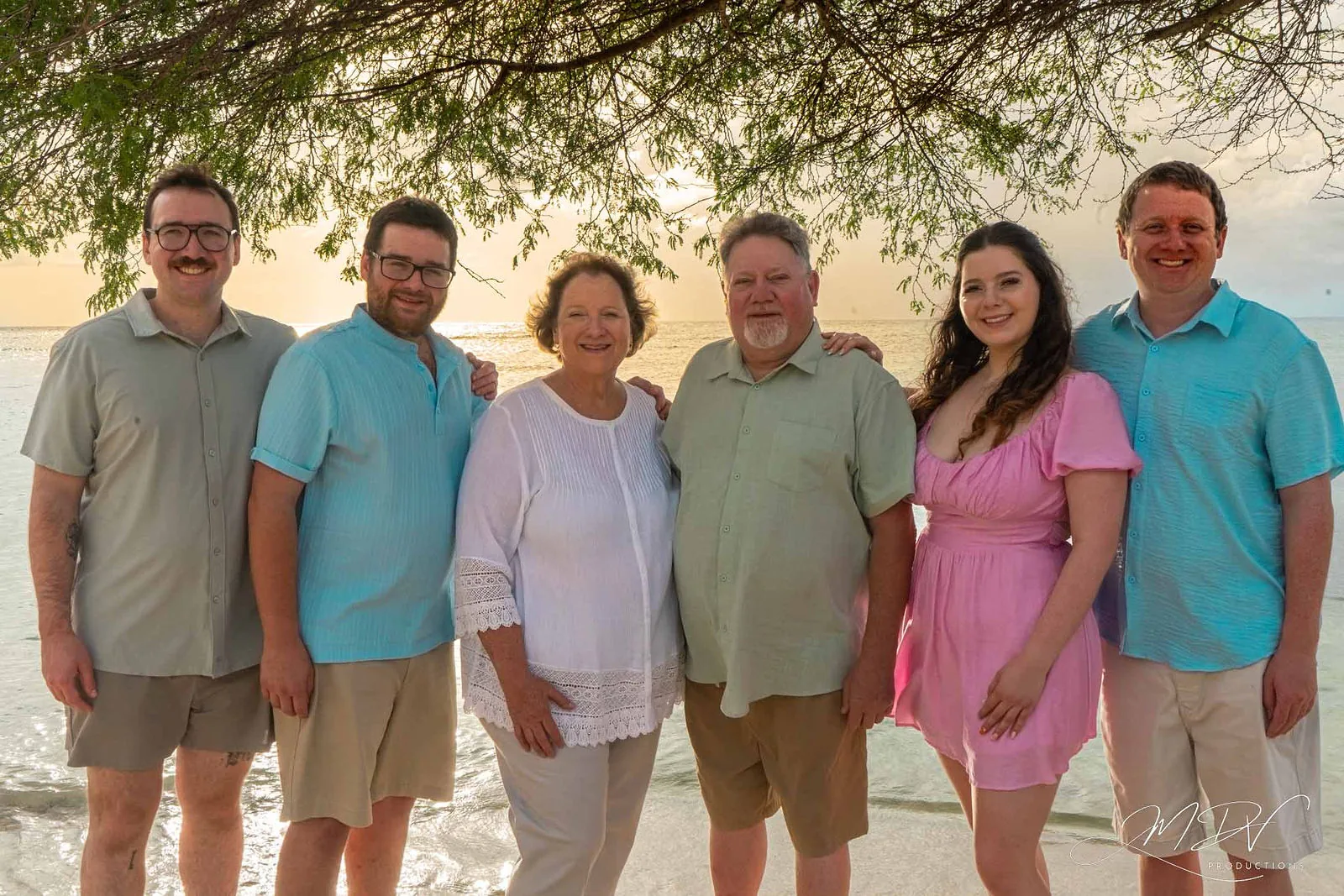 Six family members under the trees by the water at golden hour in Aruba
