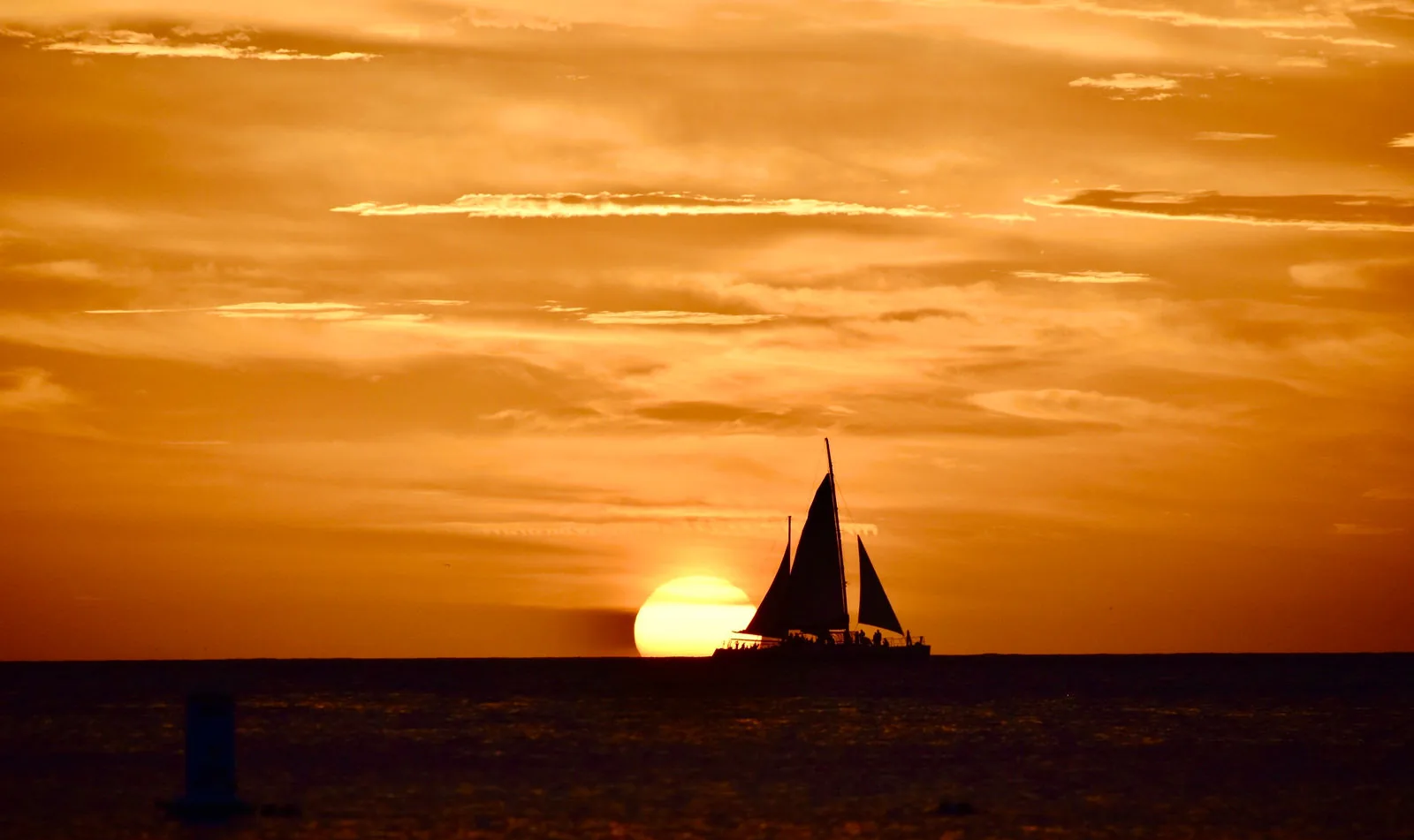 Sailboat in front of the setting sun off the coast of Aruba