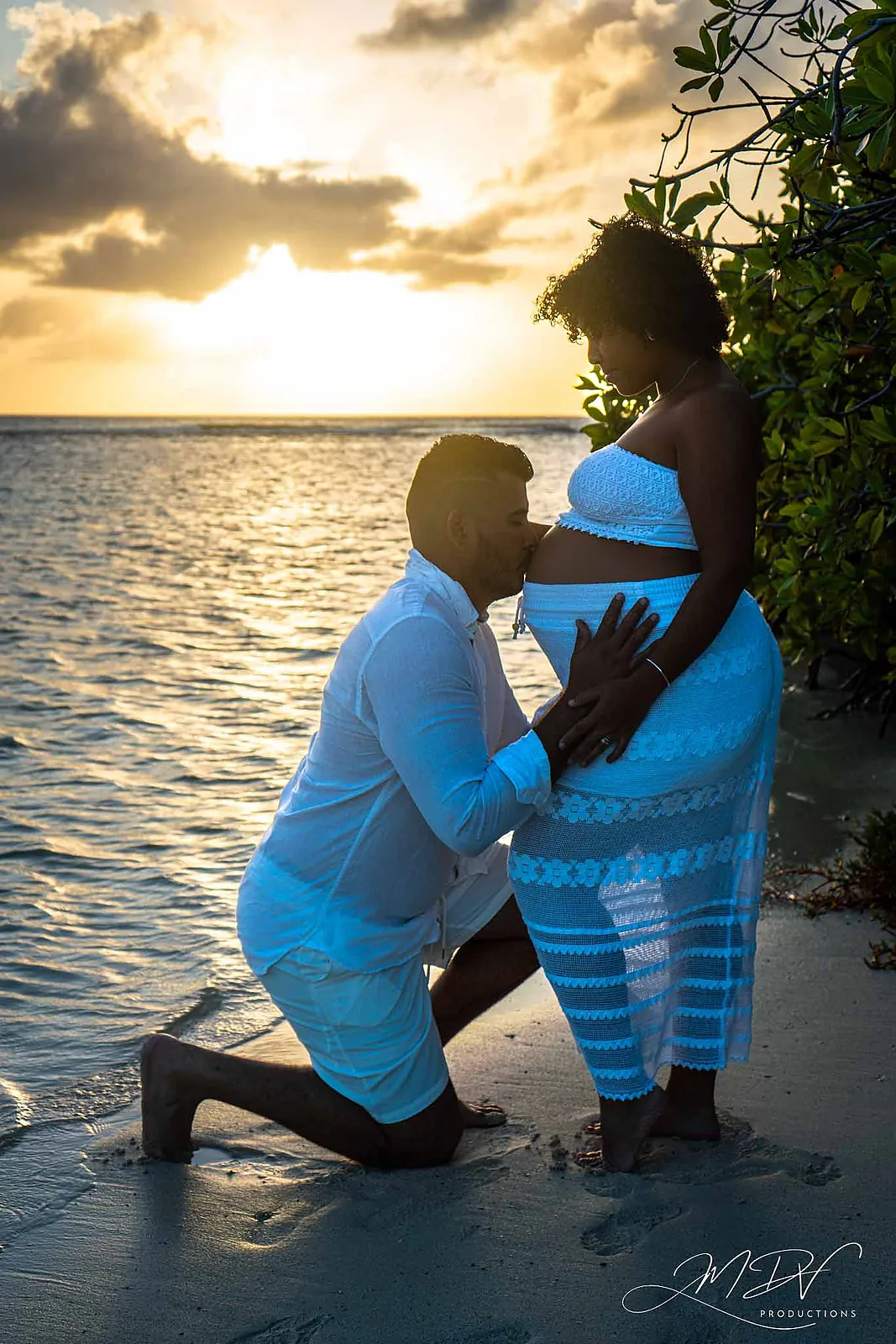 Partner kneeling to kiss the belly in the sea at sunset in Aruba