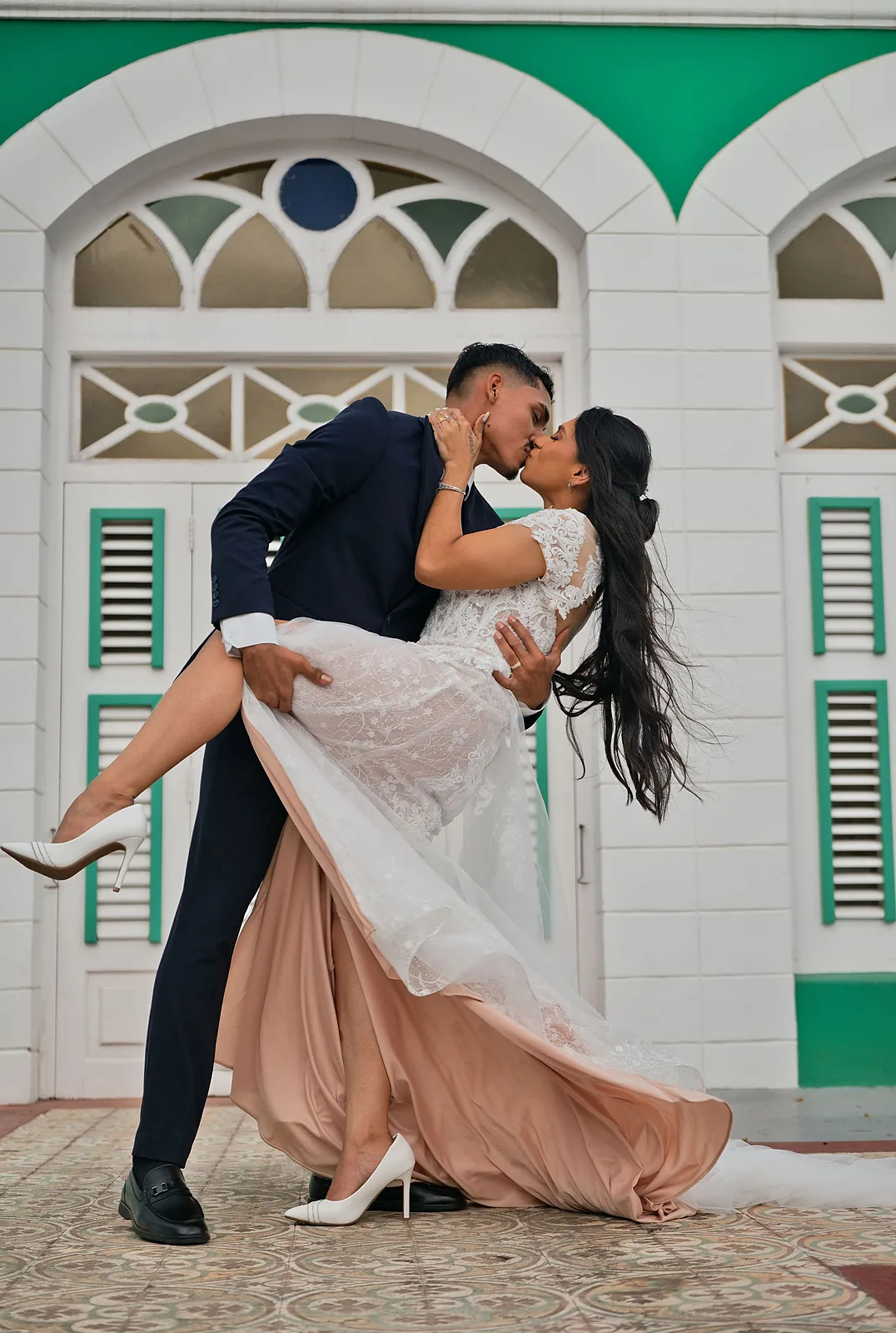 Groom dipping the bride for a kiss in front of green shutters in Aruba