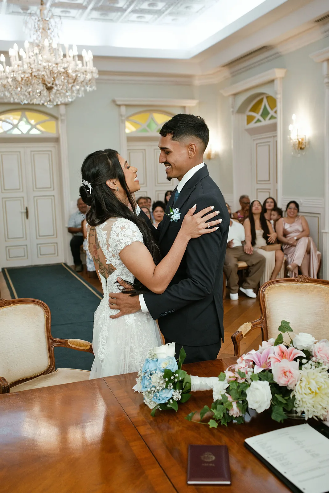 Bride and groom embracing in the wedding hall with their guests in Aruba