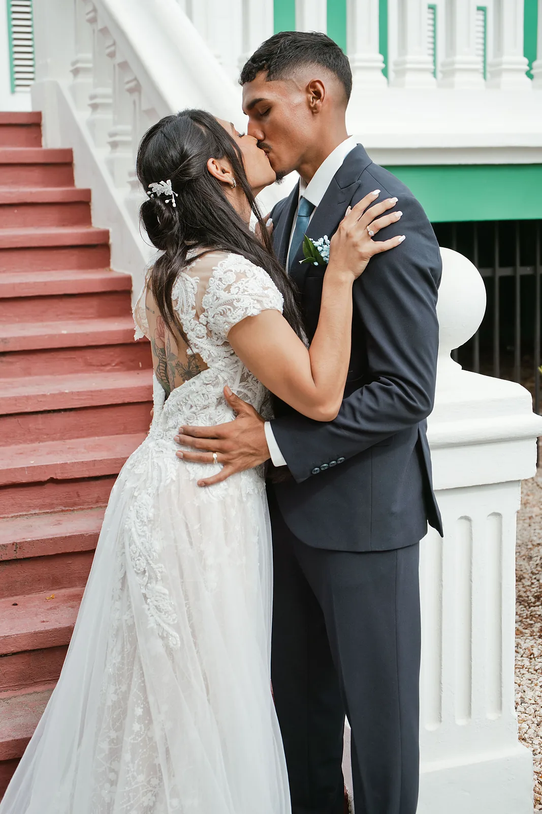 Bride and groom kissing on the steps of a colonial building in Aruba