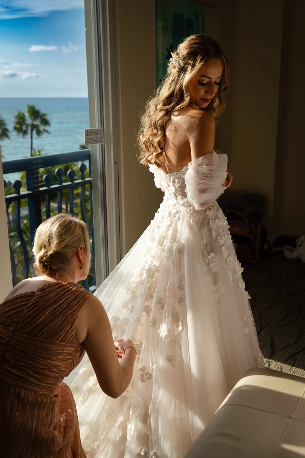 Bride getting her dress adjusted by the balcony door in Aruba