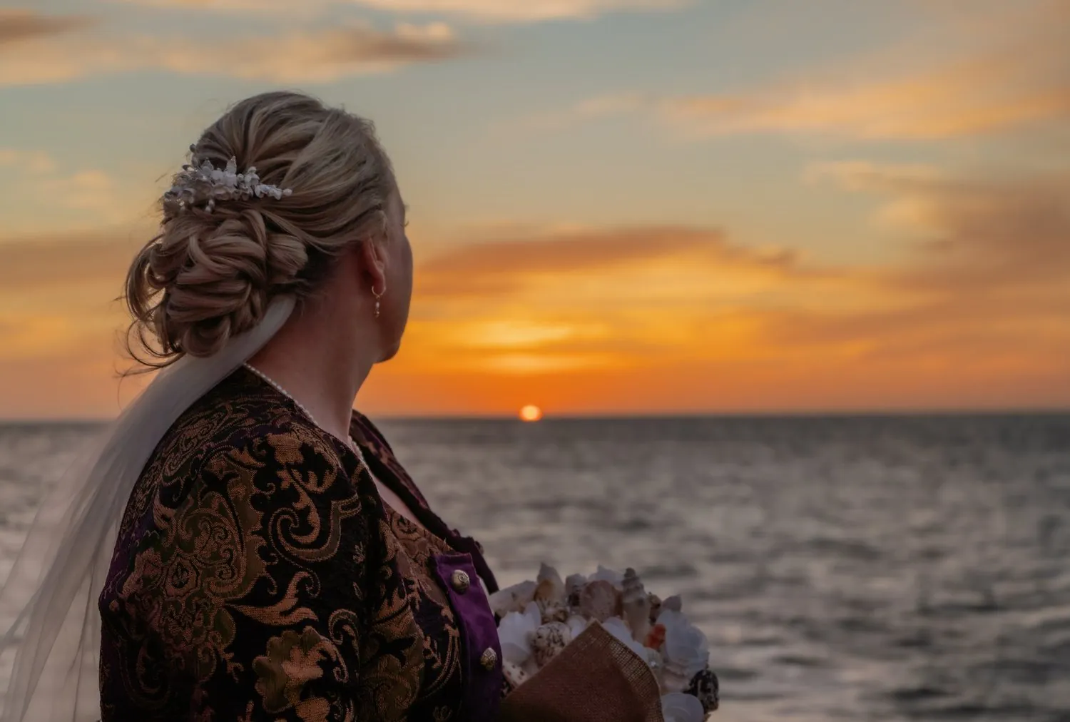 Bride with a veil looking out over the sea at sunset in Aruba
